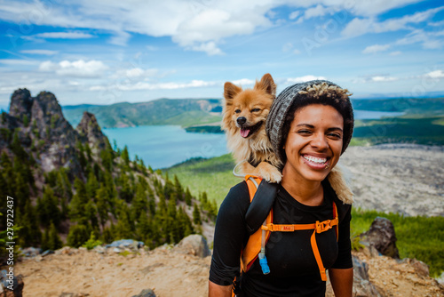 Fototapeta Girl hiking with dog in backpack