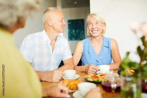 Portrait of smiling mature woman sitting at dinner table with friends and family  copy space