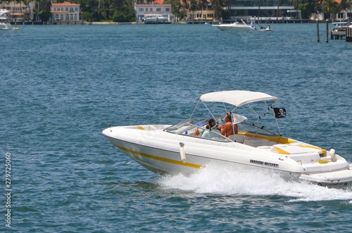 Couple speeding on the Florida Intra-Coastal Waterway in a yellow and white inboard engine motorboat © Wimbledon