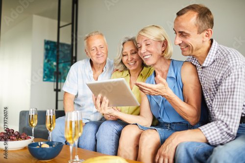Group of contemporary adult people using digital tablet sitting on sofa at home, copy space