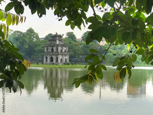 close up hoan kiem lake and turtle tower framed by trees in hanoi photo