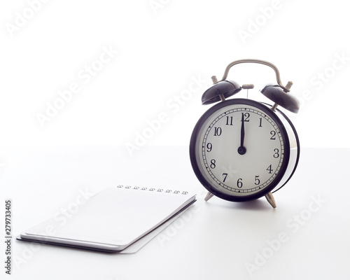 alarm clock with blank white notebook