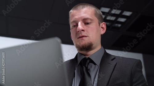 Caucasian Male Working at A Desk in a Plain White Room