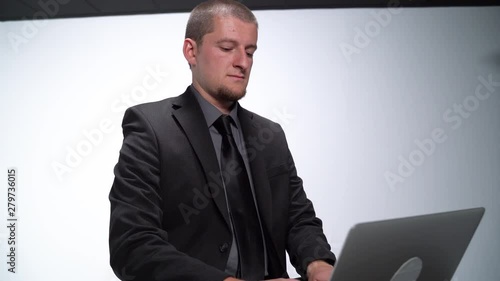 Caucasian Male Working at A Desk on a Laptop in a Plain White Room