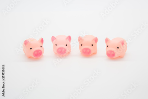 Four cute pink toy pigs lined up on a white background