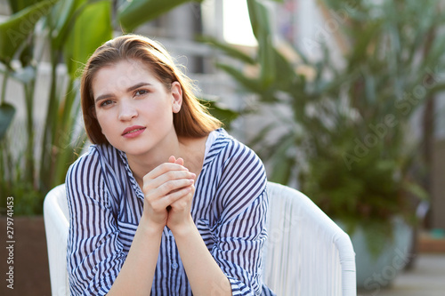 Portrait of young girl sits in the white armchair against blurred balckground photo