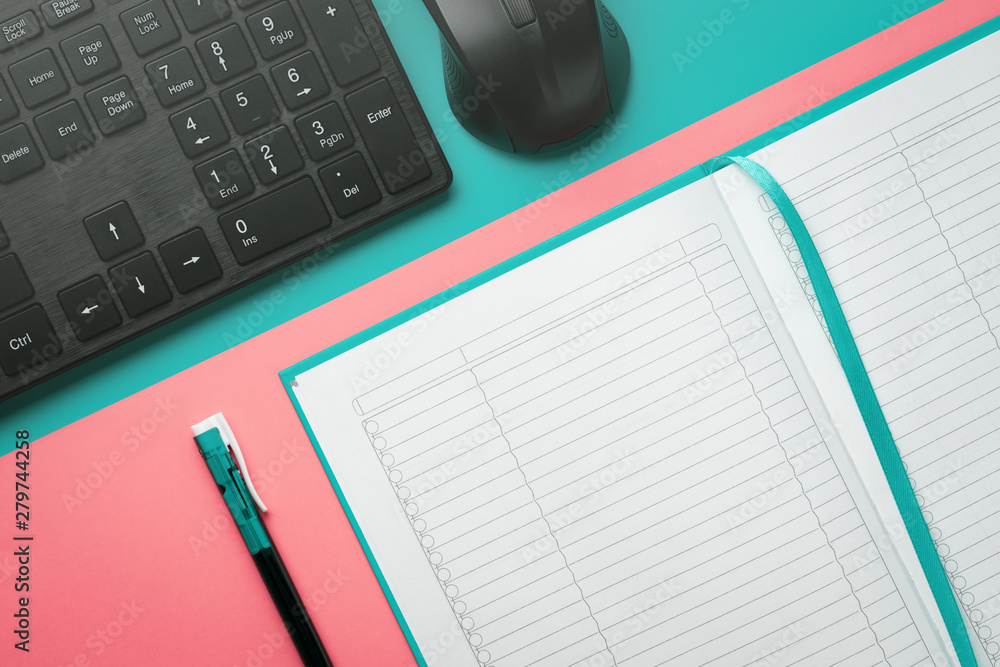 Top view notebook with a ballpoint pen and keyboard with a computer mouse on a colored background Top view notebook with a ballpoint pen and keyboard with a computer mouse on a colored background