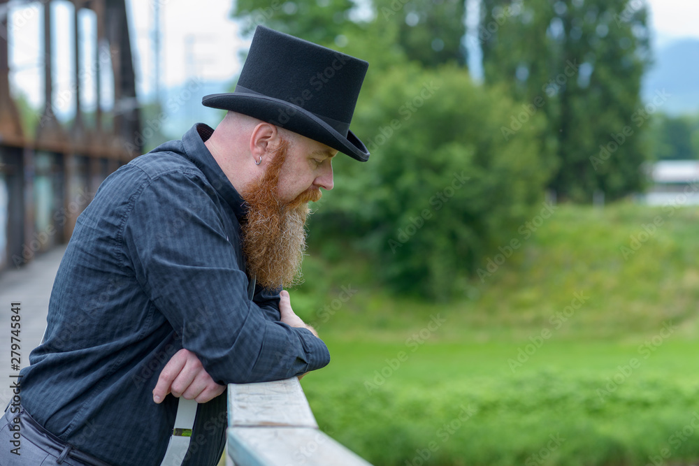 Bearded man in a top hat lost in deep thought