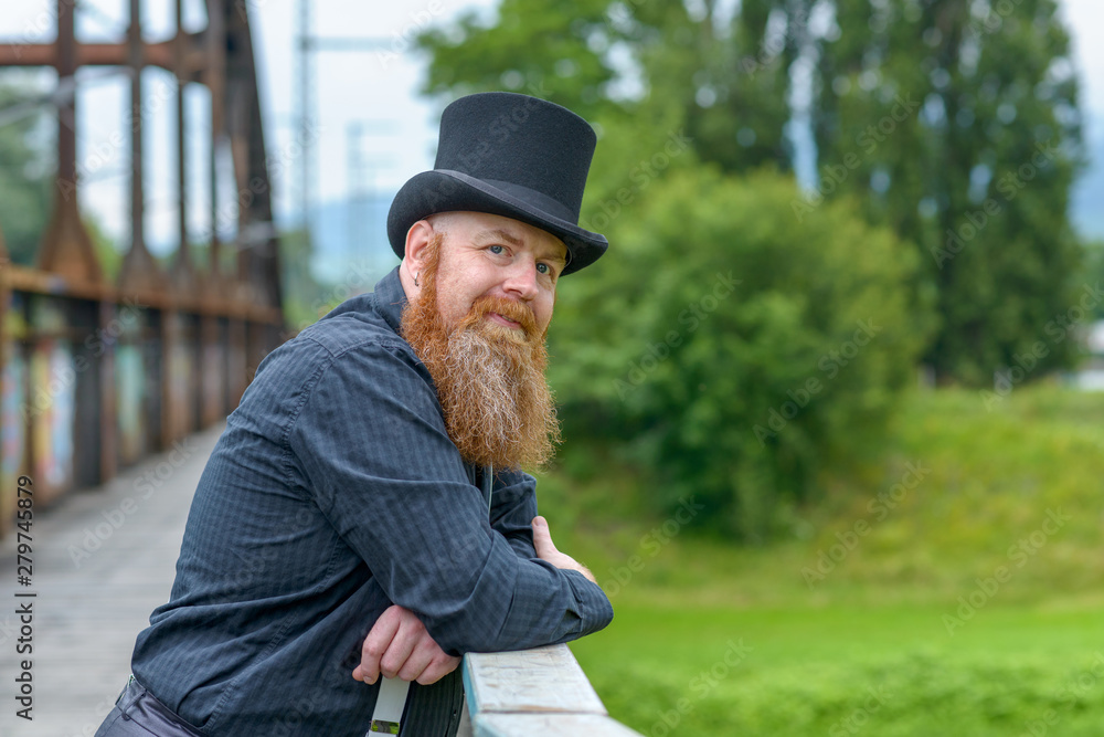 Fototapeta premium Smiling friendly bearded man leaning on a bridge