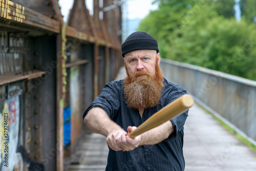 Aggressive bearded man swinging a baseball bat