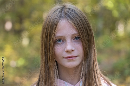 Beautiful blonde young girl with freckles outdoors on nature background in autumn, close up portrait © OlegD