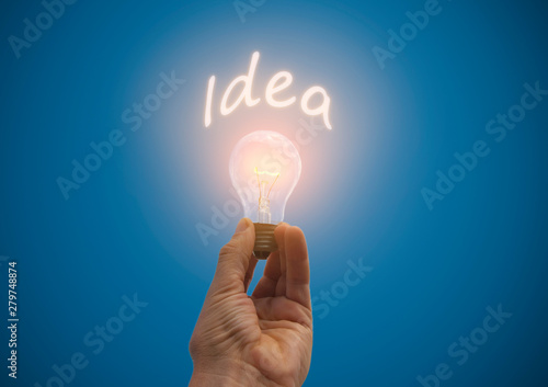 concept burning in hand light bulb with the word idea on a blue background side view