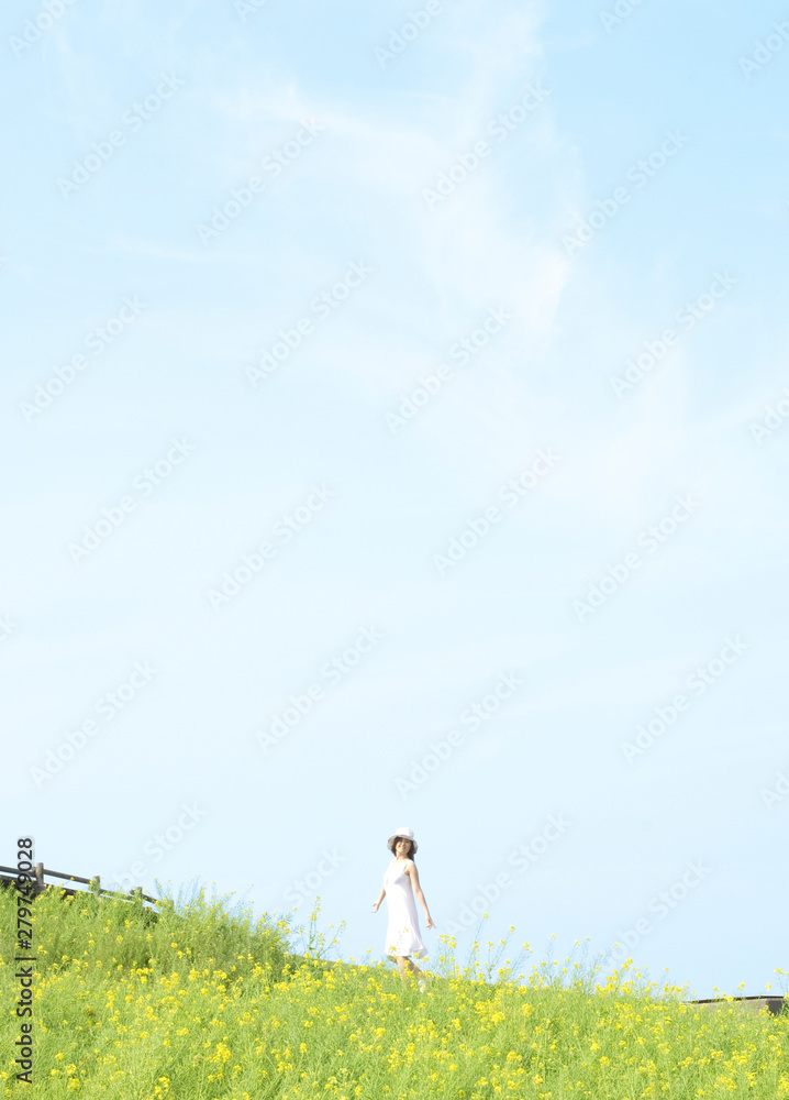 土手を歩く帽子をかぶった女性