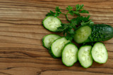 Slices of fresh green cucumber on a brown wooden background. Side view, horizontal, close-up, free space, cropped shot. Healthy eating concept.