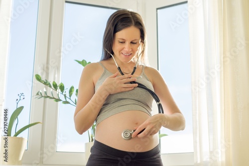 Beautiful young pregnant woman with stethoscope listening to her belly with baby Free Download Beautiful young pregnant woman with stethoscope listening to her belly with baby - GFXLoad