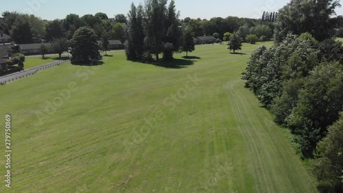 Flying over a field and trees in an urban green space on a Summer day in Manchester, England.