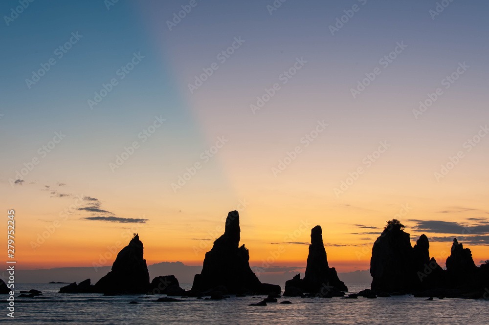 岩が並ぶ海岸の空に現れた光の筋