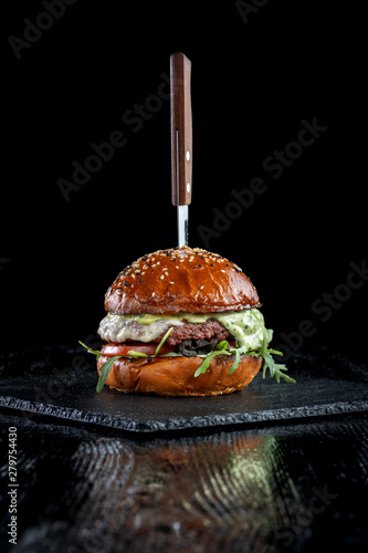 Burger with olives, tomatoes, herbs and pesto.