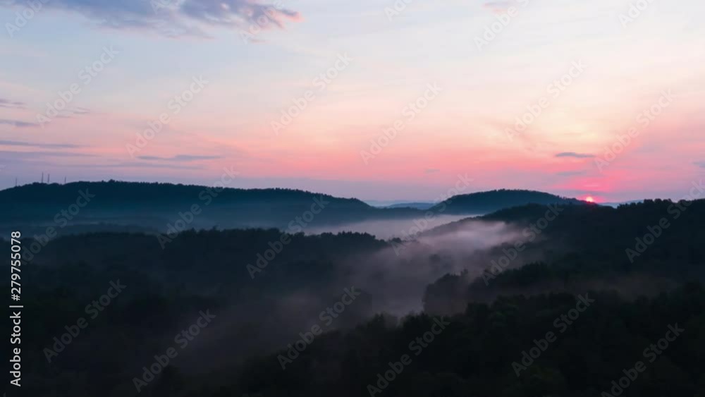 Early morning foggy sunrise timelapse in the woods. Fog rolling through the trees and sun rising above them. Early morning foggy sunrise timelapse in the woods. Fog rolling through the trees and sun rising above them.