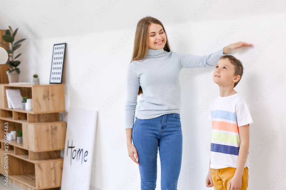 Mother measuring height of her son near wall Mother measuring height of her son near wall