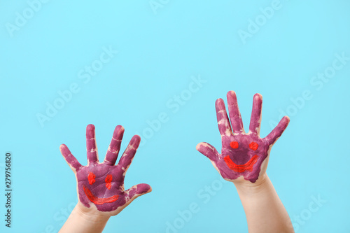 Child's hands in paint on color background