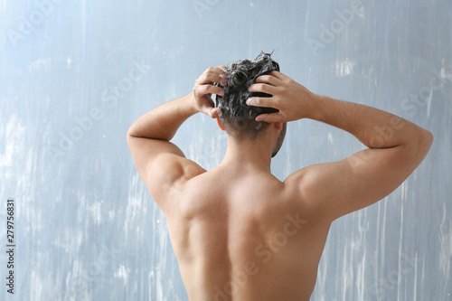 Handsome man washing hair o...