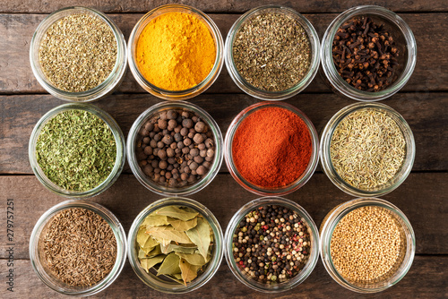 Collection of spices in bowls on wooden background. Top view