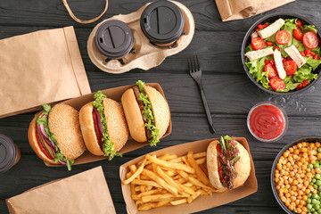Different tasty food from delivery service on wooden background