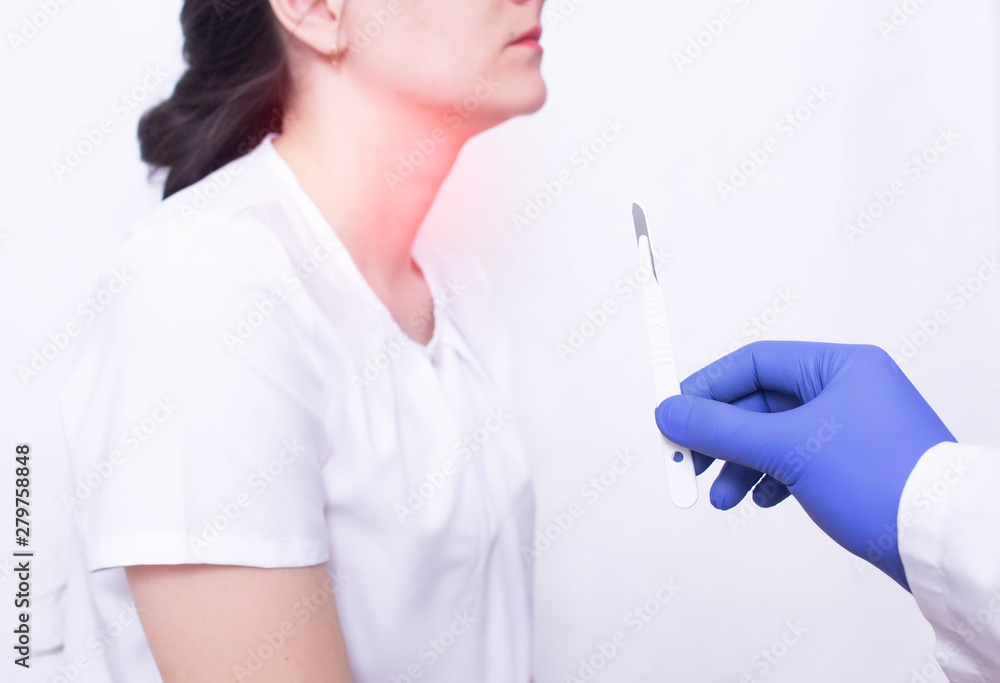 Fototapeta premium Doctor holding a surgical scalpel on the background of a girl with throat disease, concept of removing adenoids by surgery, surgery for throat diseases