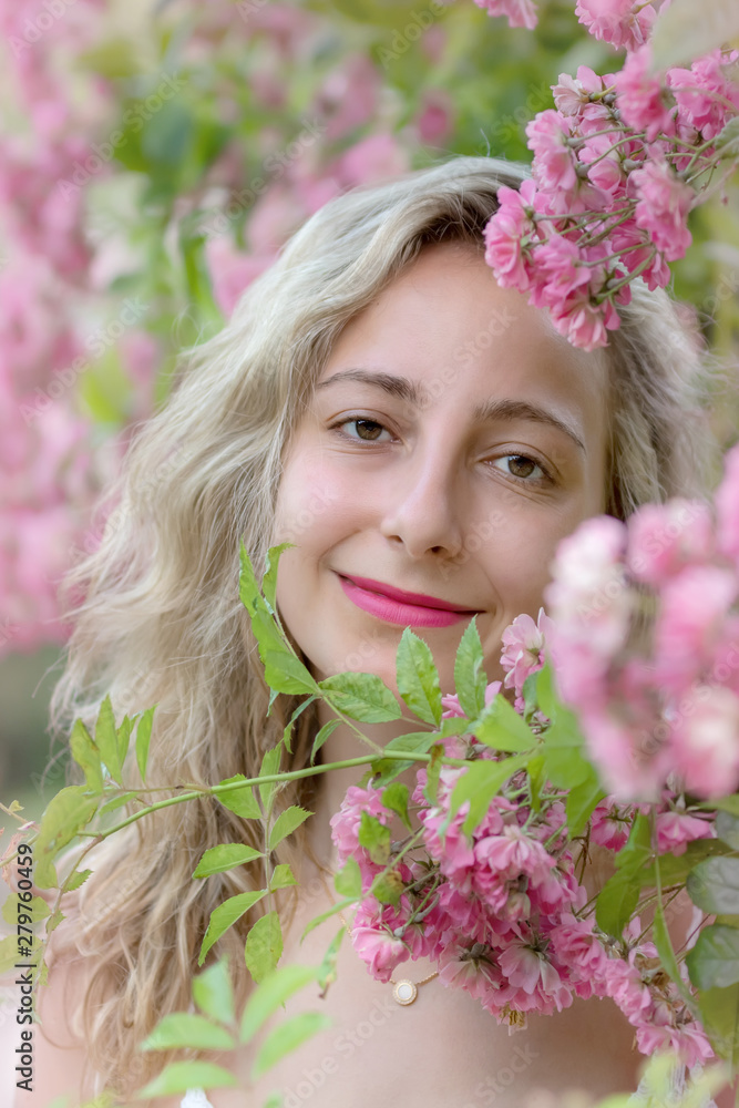 Fototapeta premium Portrait of a young woman in a park of roses