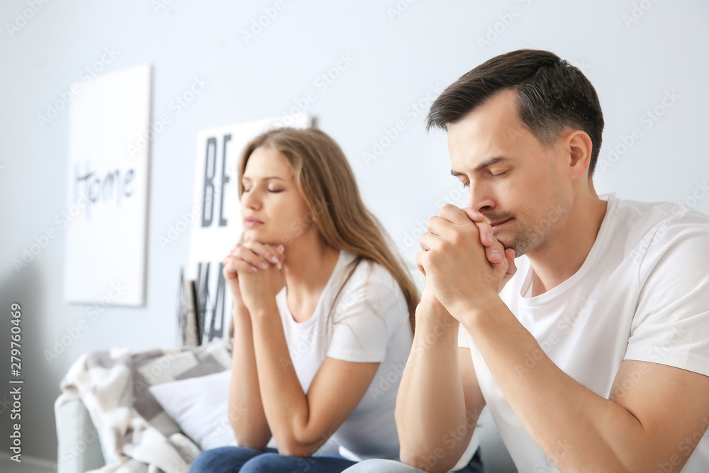 Religious couple praying to God at home