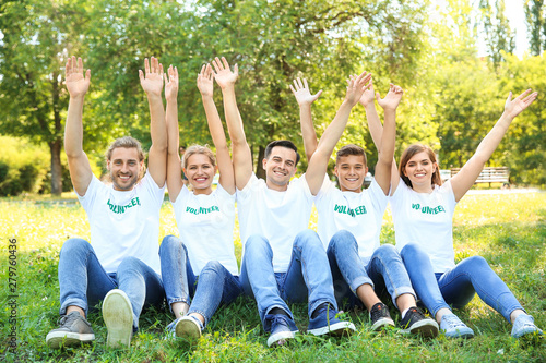 Group of volunteers sitting on green grass outdoors