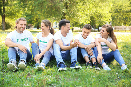 Group of volunteers sitting on green grass outdoors