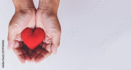 heart on hand for philanthropy / woman holding red heart in hands for valentines day or donate help give love warmth take care photo