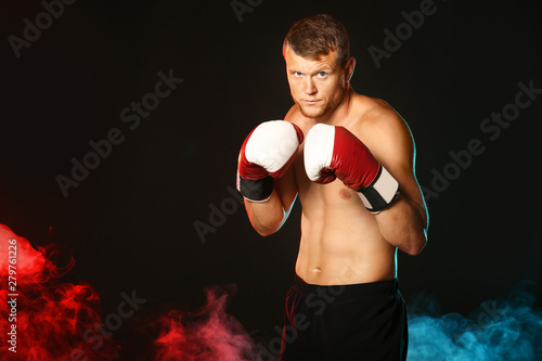 Strong male boxer on dark b...