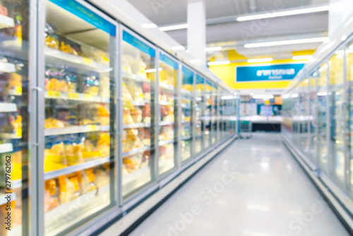 Frozen food on shelf in freezers at supermarket. Blurred background for your design.