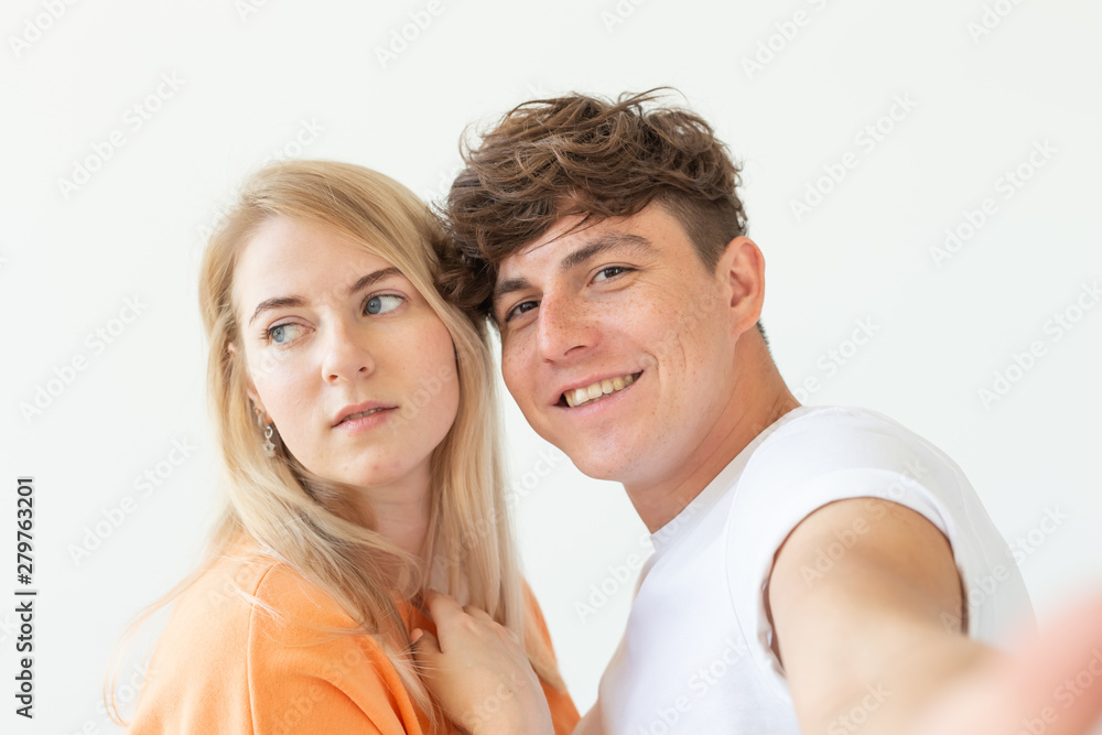 Portrait of a cute positive cheerful young couple of students taking selfie on a smartphone or camera. The concept of a passionate young couple in love with students. Portrait of a cute positive cheerful young couple of students taking selfie on a smartphone or camera. The concept of a passionate young couple in love with students.
