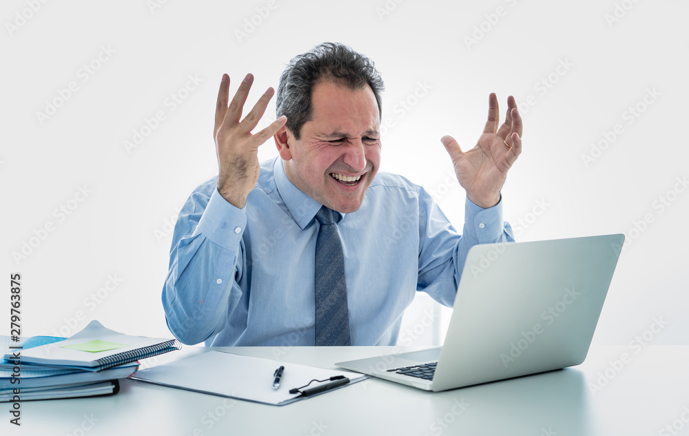 Overwhelmed and desperate mature businessman working with laptop feeling angry and furious at office Overwhelmed and desperate mature businessman working with laptop feeling angry and furious at office