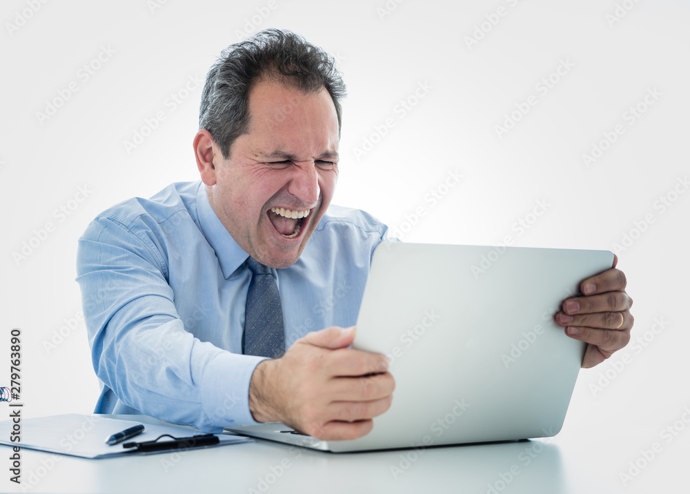 Overwhelmed and desperate mature businessman working with laptop feeling angry and furious at office Overwhelmed and desperate mature businessman working with laptop feeling angry and furious at office