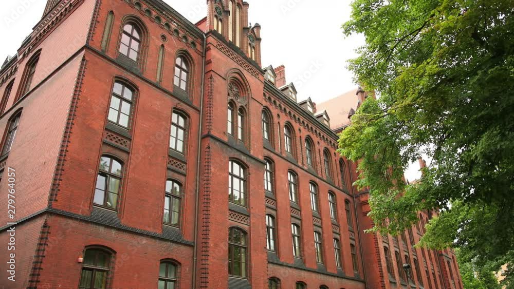 Camera movement apartment block of red brick, for office or dwelling. Many windows, in the foreground of the branches of the tree with green leaves. Wide angle, prores, slow motion Camera movement apartment block of red brick, for office or dwelling. Many windows, in the foreground of the branches of the tree with green leaves. Wide angle, prores, slow motion