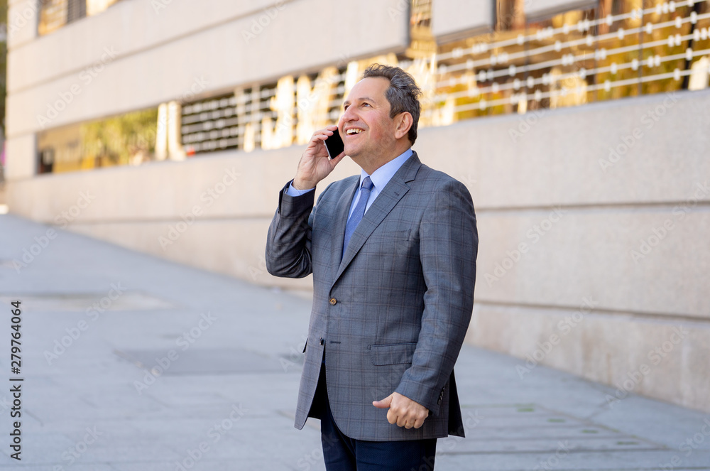 Portrait of handsome middle aged smart businessman walking in the city talking on mobile phone Portrait of handsome middle aged smart businessman walking in the city talking on mobile phone