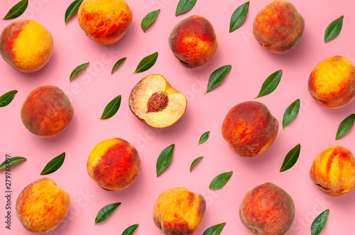 Flat lay composition with peaches. Ripe juicy peaches with green leaves on pink background. Flat lay, top view, copy space. Creative peaches pattern. Fresh organic food. Harvest concept