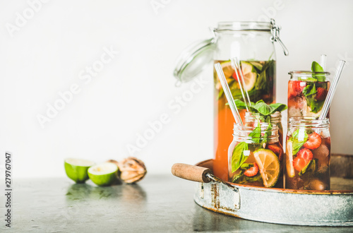 Homemade strawberry and basil lemonade or ice tea in glass tumblers with eco-friendly plastic-free straws on rustic metal tray, white wall at background, copy space. Summer cold refreshing soft drink