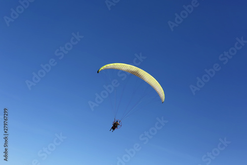 Man fly over blue sky as paragliding extreme sport 