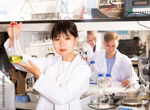 Fototapeta Naklejka Na Ścianę i Meble -  Young Chinese female scientist holding flask