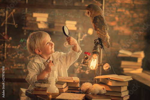 scoolboy in white coat looking at owl in magnifying glass
