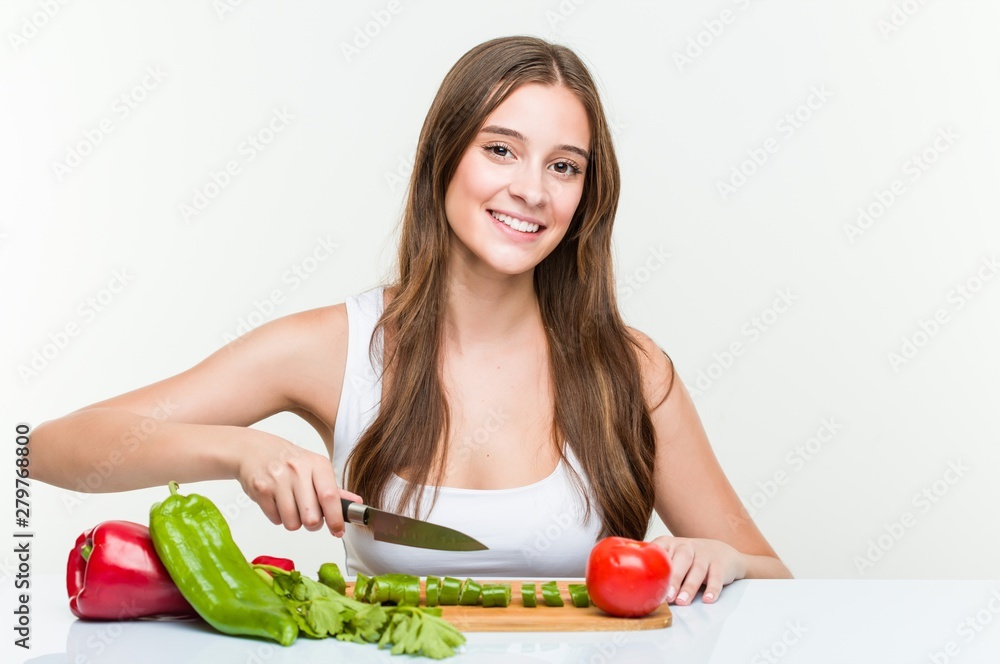 Young caucasian woman holding a knife and cutting vegetables Young caucasian woman holding a knife and cutting vegetables