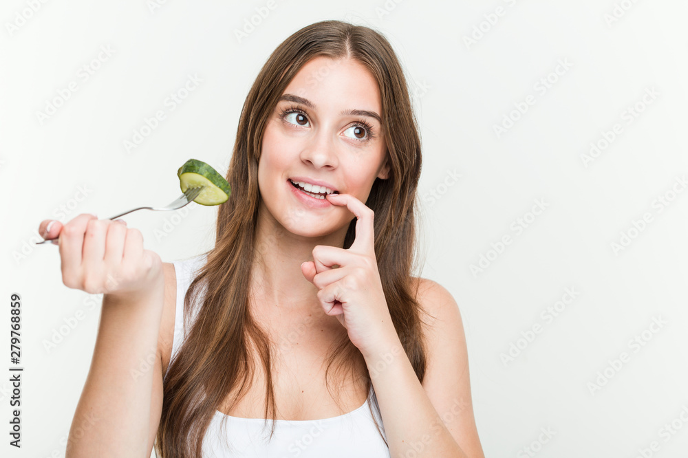 Young caucasian woman eating cucumber relaxed thinking about something looking at a copy space. Young caucasian woman eating cucumber relaxed thinking about something looking at a copy space.