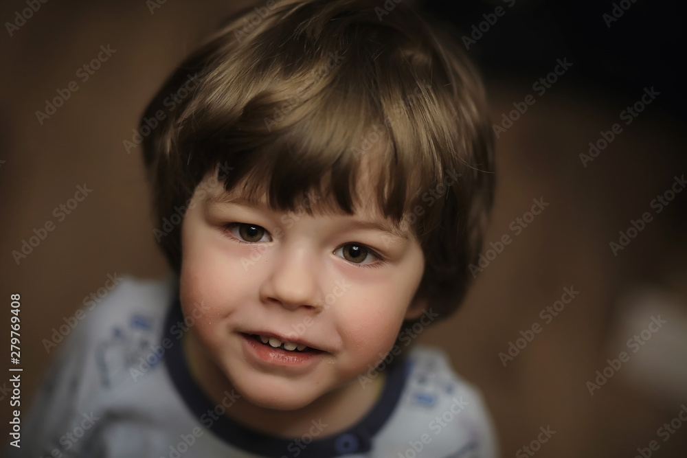 Portrait of a small curly-haired boy. A child wrapped in a rug eats an apple. A two-year-old boy hides under a blanket. Portrait of a small curly-haired boy. A child wrapped in a rug eats an apple. A two-year-old boy hides under a blanket.