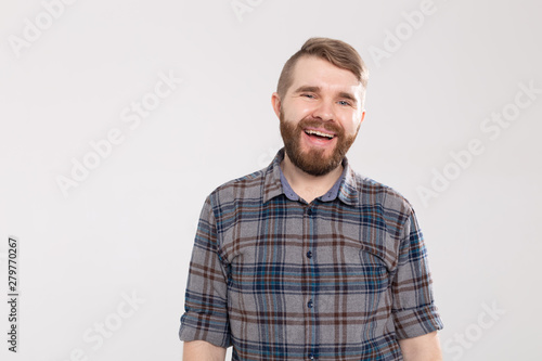 Smiling bearded young man rejoices coming weekends, dressed casually, over white background with copy space. Positive pleased student.